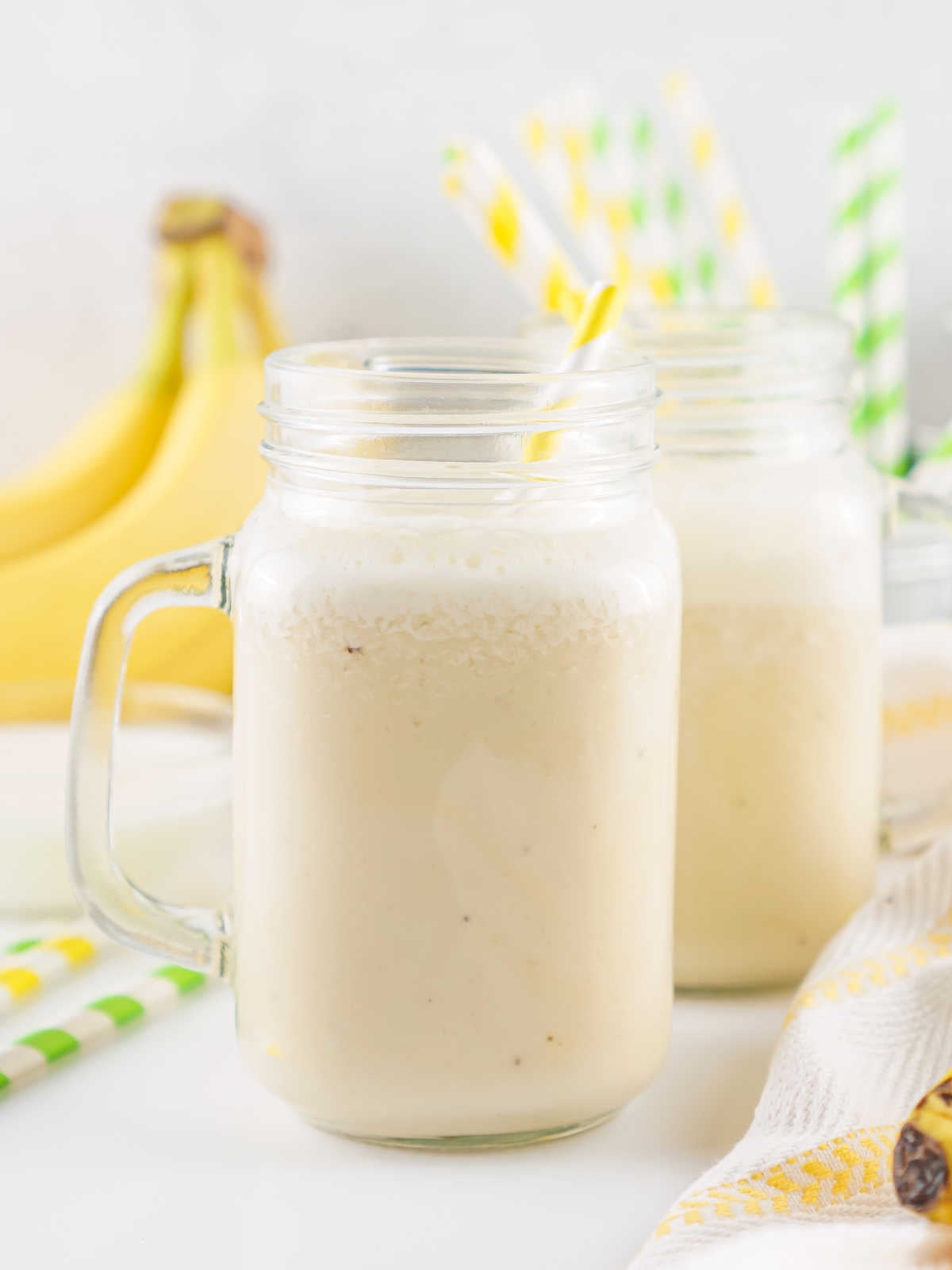 Glasses of freshly made banana milk with more bananas in the background. 