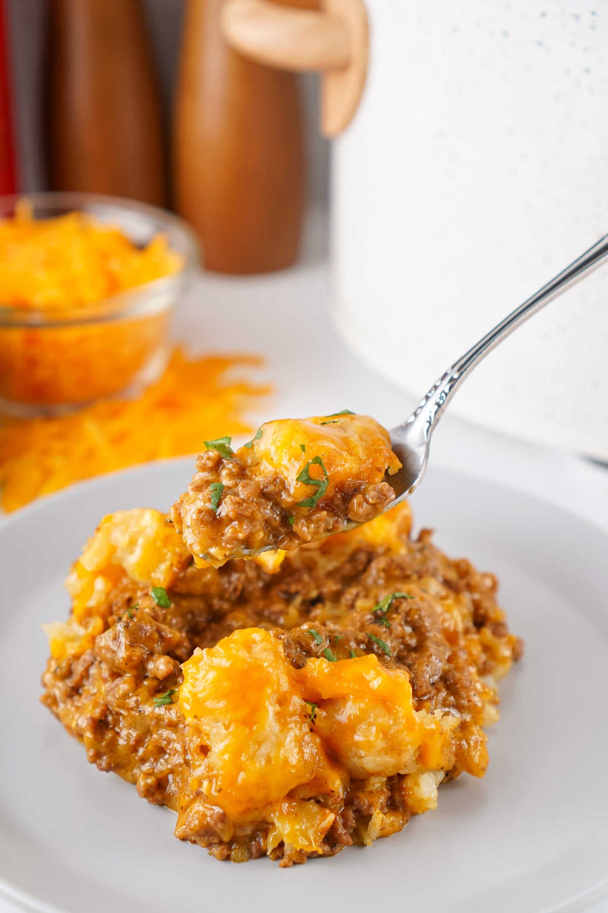 Fork getting a bite of tater tot casserole with taco meat and cheese. 