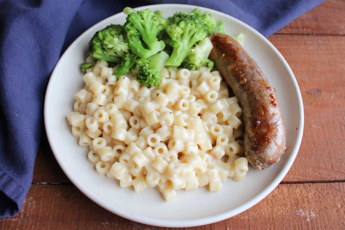 Creamy One Pot Ditalini Pasta With Parmesan Cheese 9 Dinner plate with creamy ditalini pasta, and Italian sausage link, and broccoli, ready to eat.