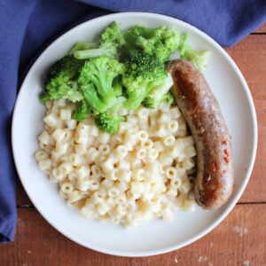 Creamy One Pot Ditalini Pasta With Parmesan Cheese 11 Dinner plate with an Italian sausage link, broccoli, and a generous helping of creamy parmesan ditalini pasta.