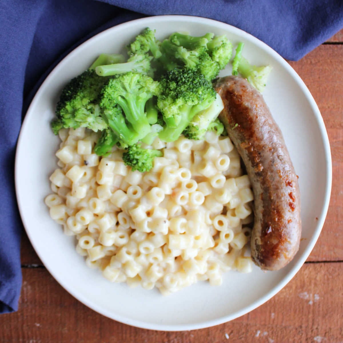 Creamy One Pot Ditalini Pasta With Parmesan Cheese 5 Dinner plate with an Italian sausage link, broccoli, and a generous helping of creamy parmesan ditalini pasta.