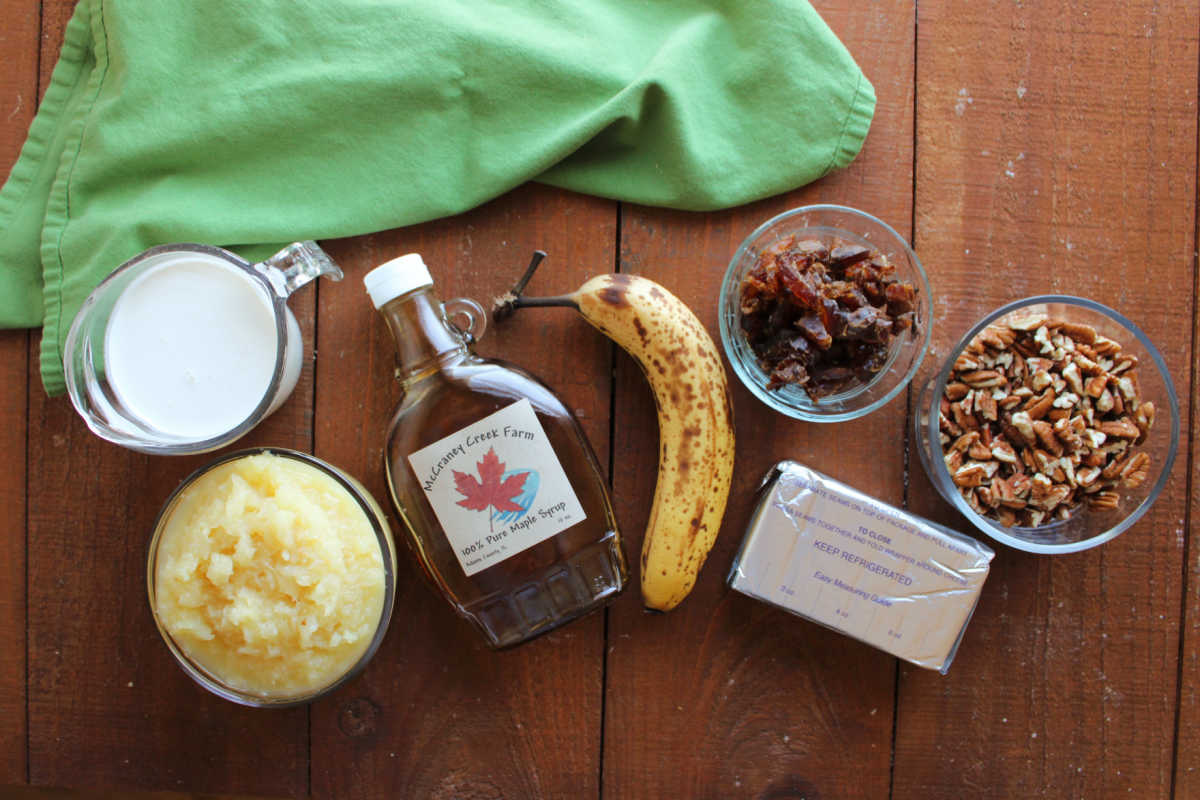 Ingredients including dates, pecans, a banana, crushed pineapple, cream cheese, maple syrup and heavy cream ready to be made into a frozen fruit salad. 