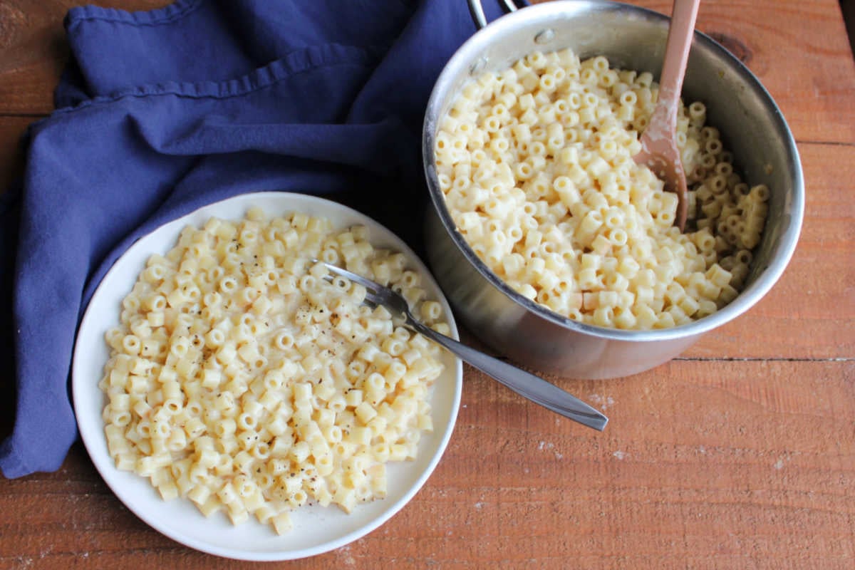 Creamy One Pot Ditalini Pasta With Parmesan Cheese 8 Plate of creamy one pot ditalini pasta next to the saucepan it was cooked in with more pasta inside.