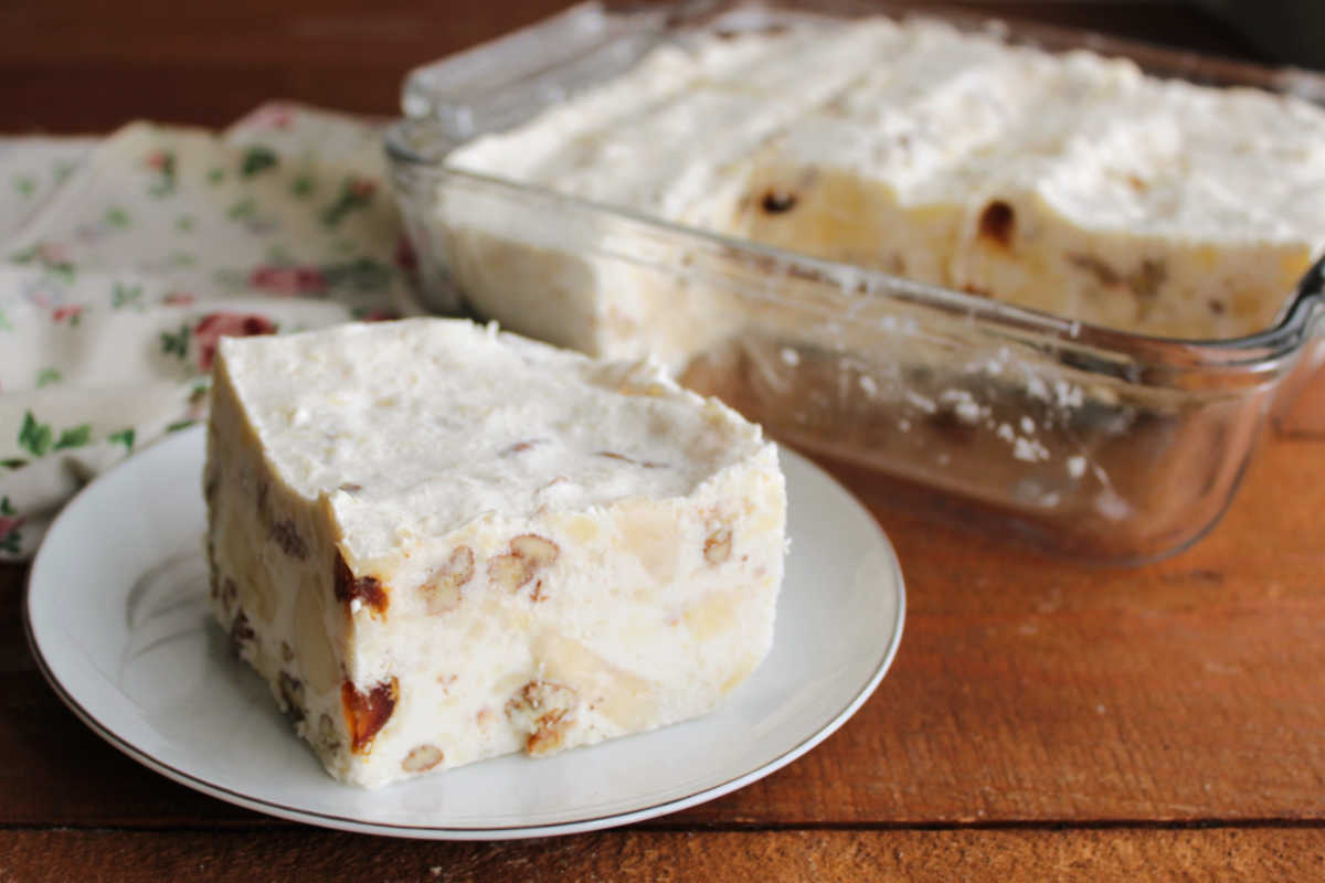 Piece of great-grandma's frozen date and cream cheese salad showing bits of fruits and nuts suspended in creamy frozen base.