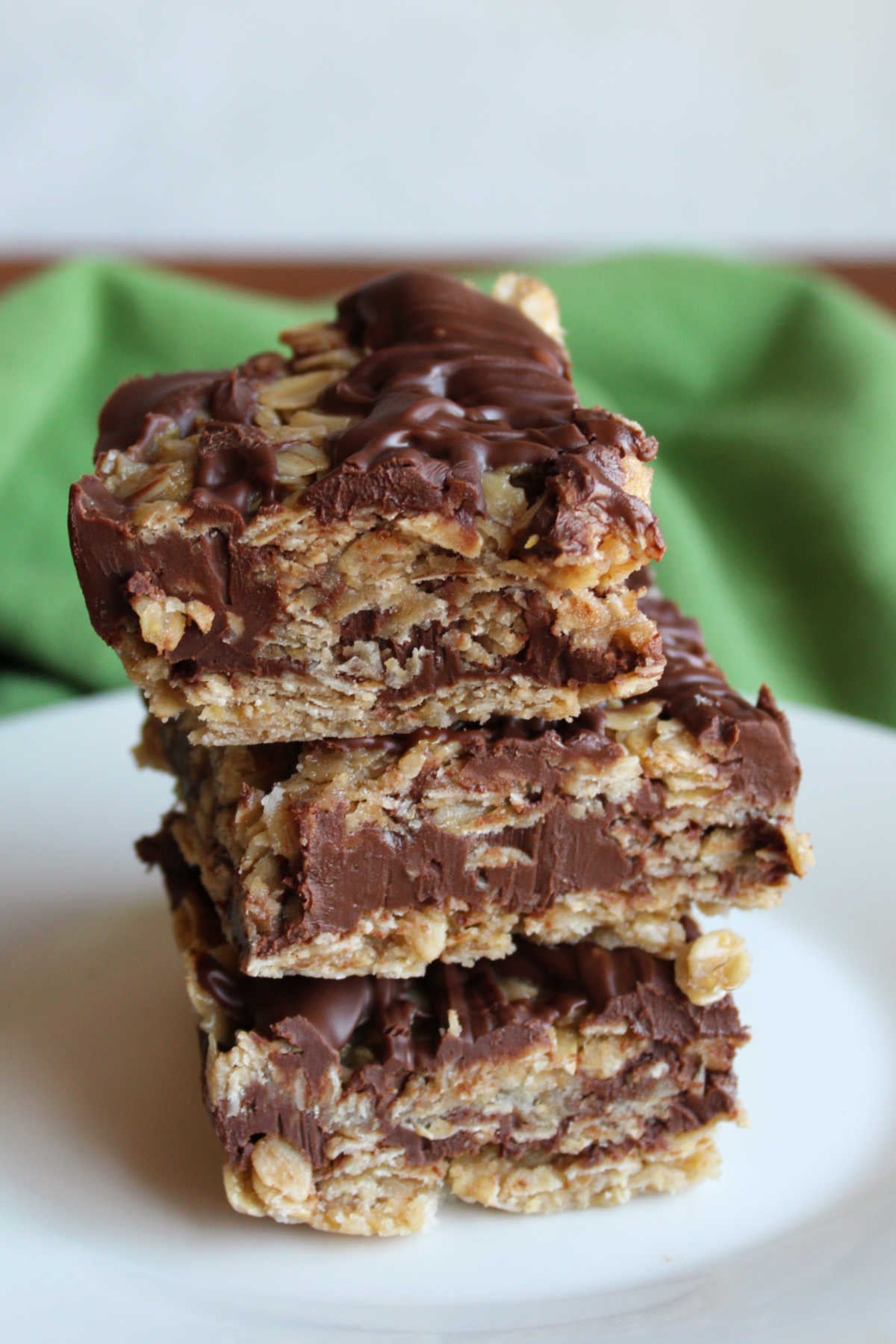 No bake oatmeal cookie bars with layers of oat mixture around a chocolate and peanut butter layer stacked on top of each other.