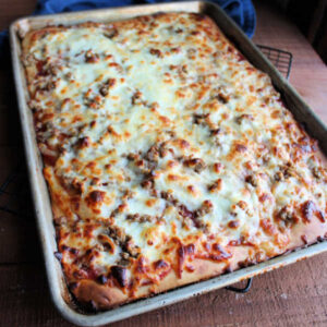 Baked pizza with melted and browned cheese, ready to be sliced and served.