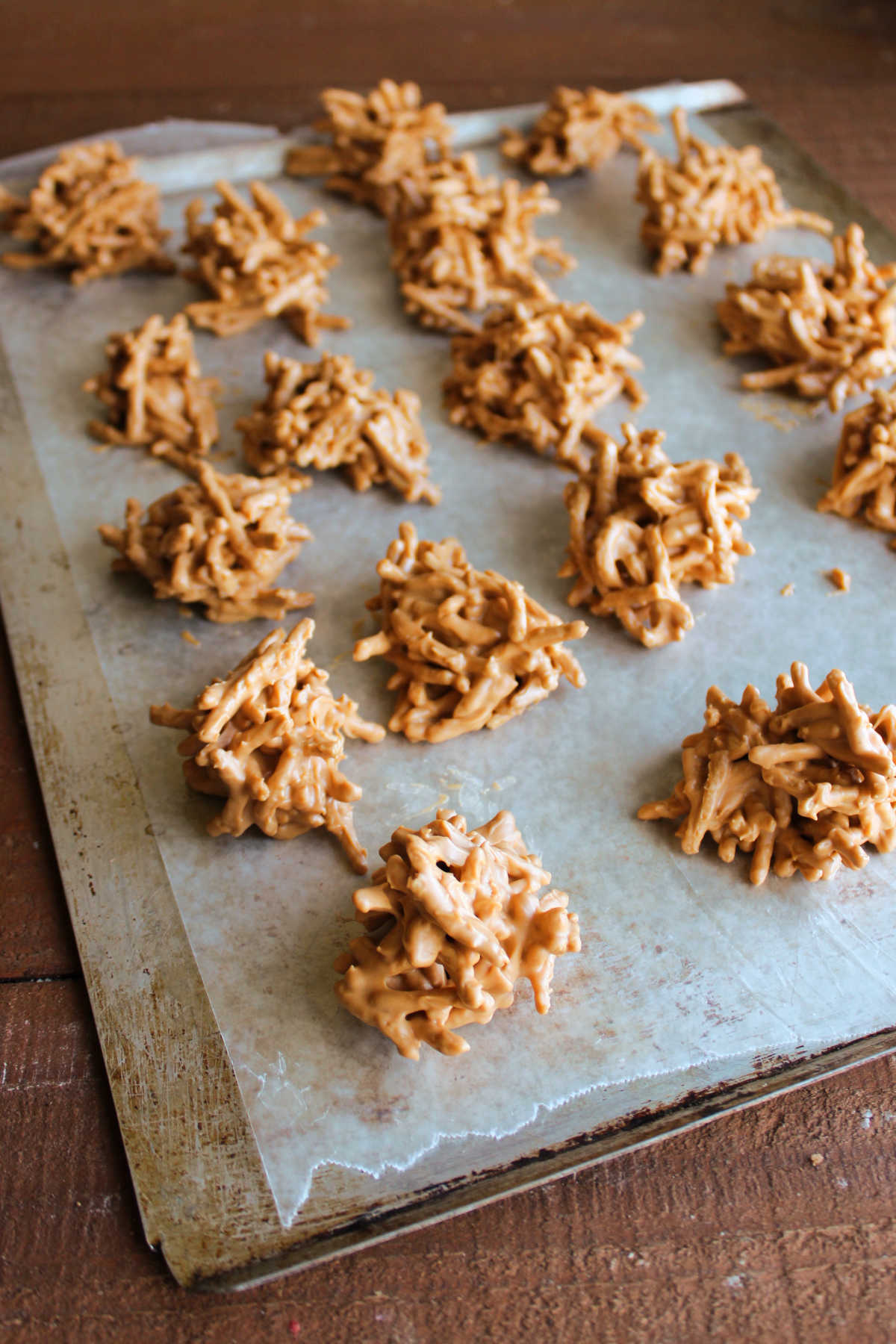 Wax paper lined baking tray of freshly scooped butterscotch haystack cookies setting up so they are ready to be served. 