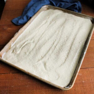 Pizza dough batter with little lumps in it spread in greased half sheet pan.