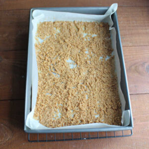 Thin layer of butter soaked graham cracker crumbs in the bottom of a parchment paper lined 9x13-inch pan.