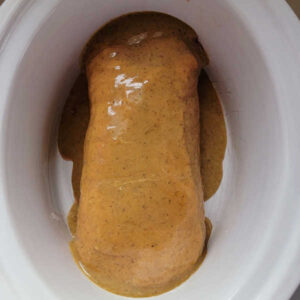 Pork loin covered in honey mustard sauce in crockpot.