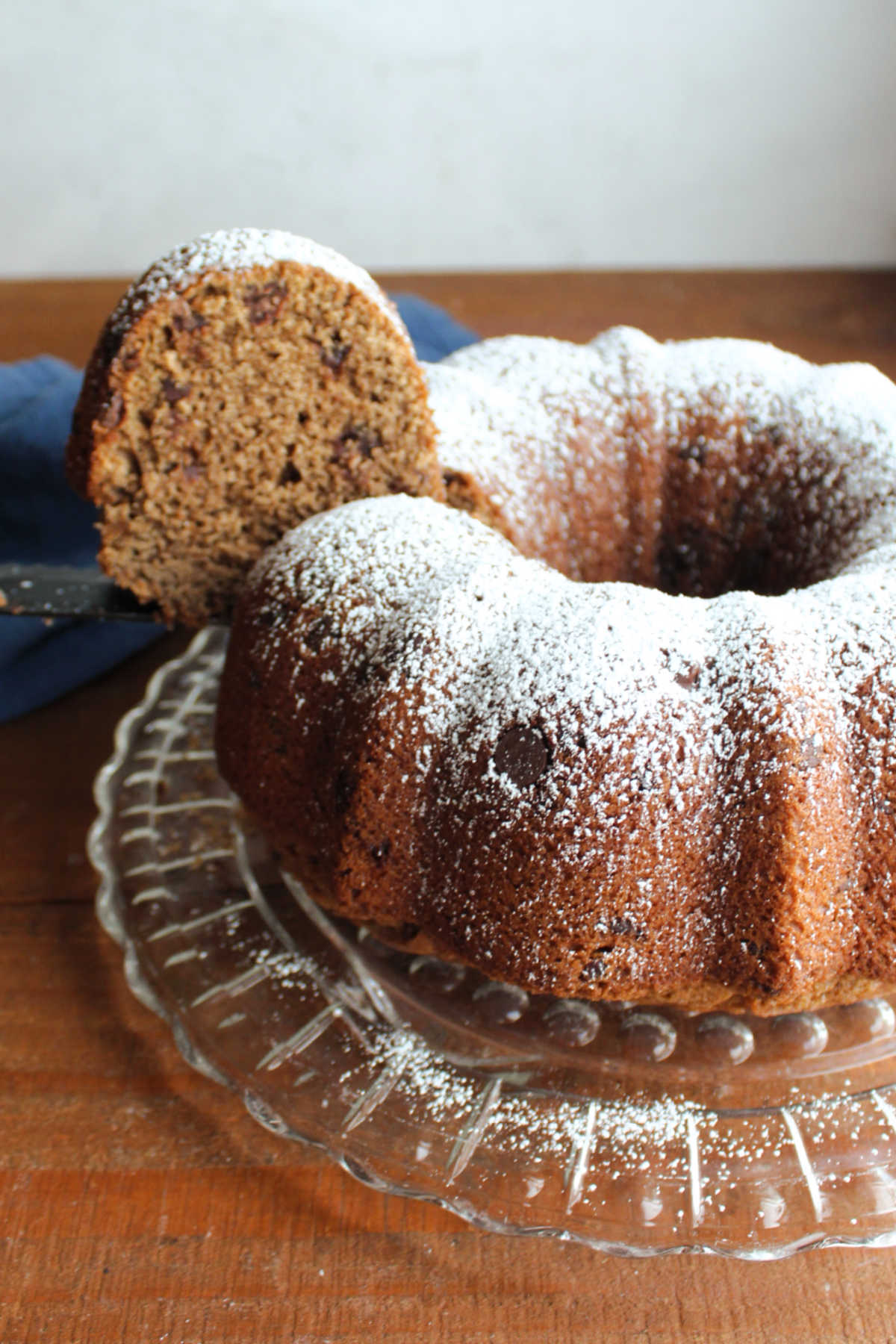 Knife lifting piece of sourdough mocha coffee cake out of the bundt cake showing powdered sugar dusting on top and soft texture inside. 