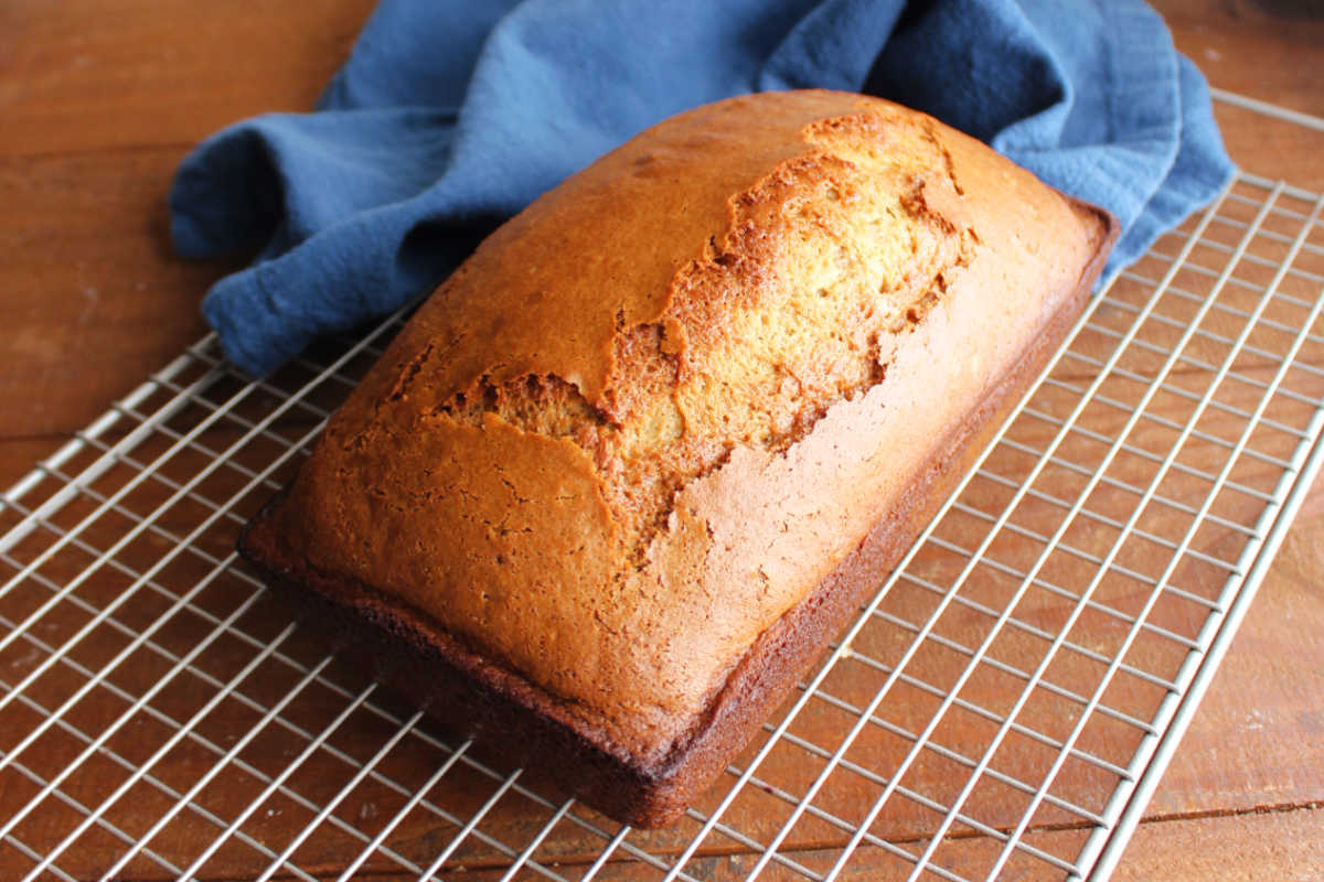 A loaf of freshly baked peanut butter bread on a cooling rack showing the golden brown exterior. 