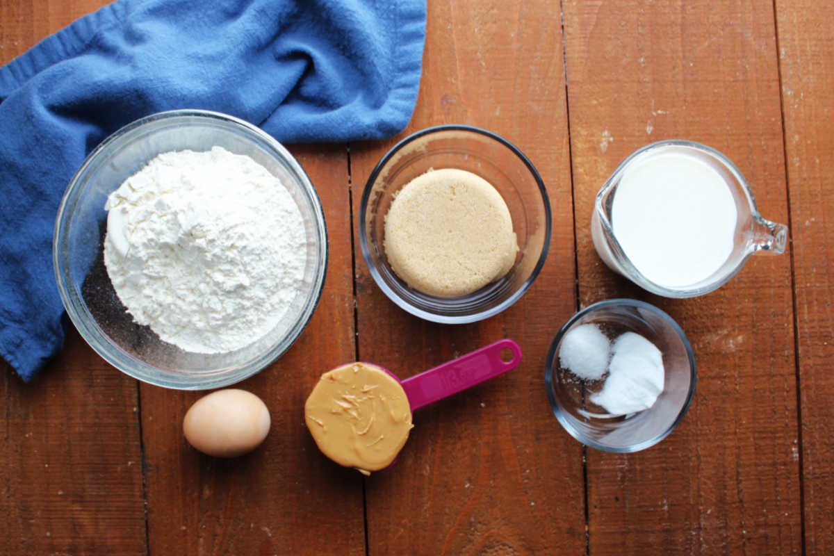 Ingredients including flour, brown sugar, milk, an egg, peanut butter, salt, and baking powder ready to be made into peanut butter quick bread. 