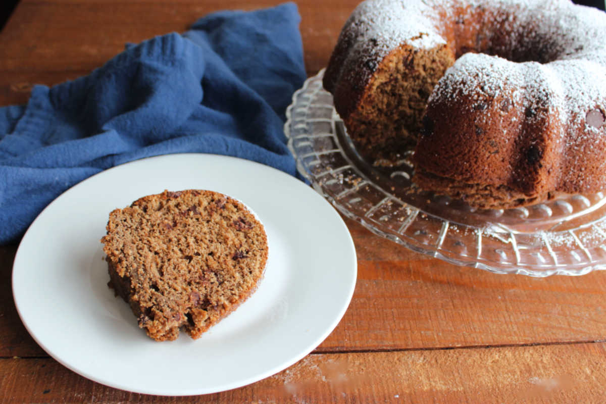 Piece of sourdough mocha quick bread on plate with remaining cake in background. 