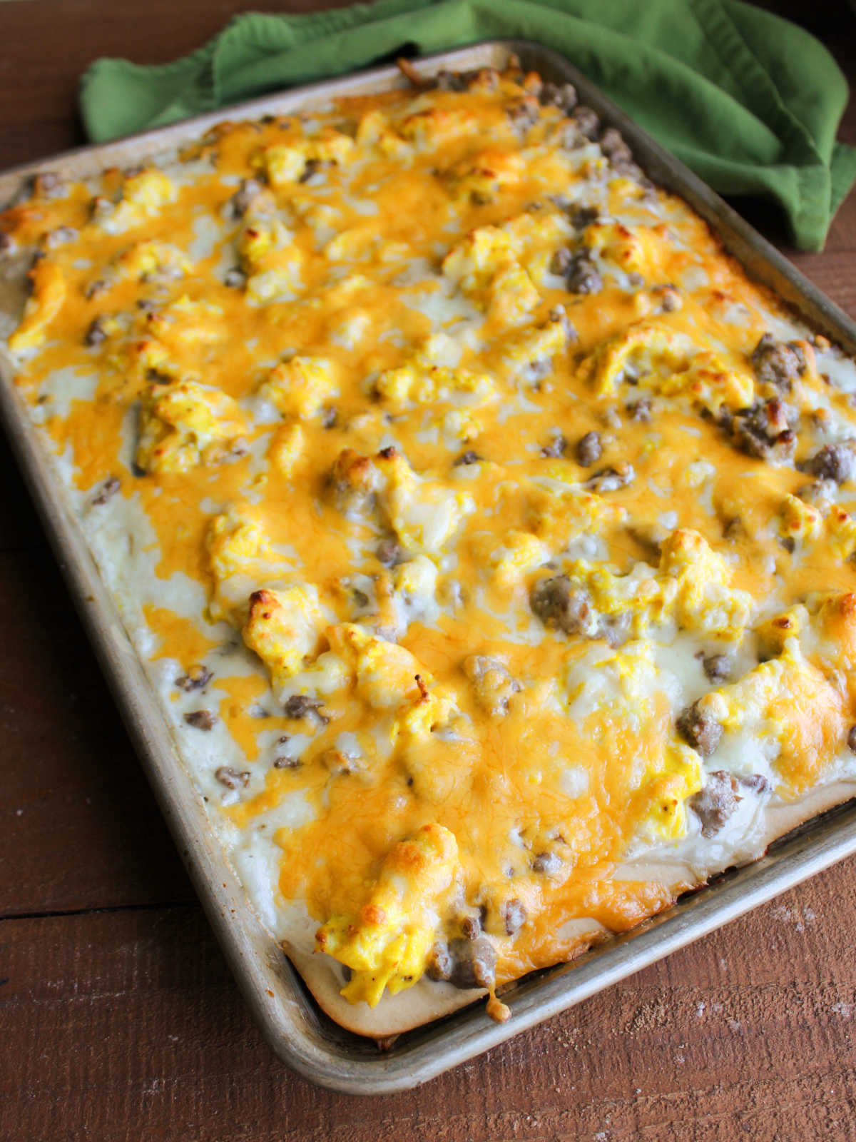 Freshly baked breakfast pizza with melty cheese in a sheet pan, ready to be cut and served. 