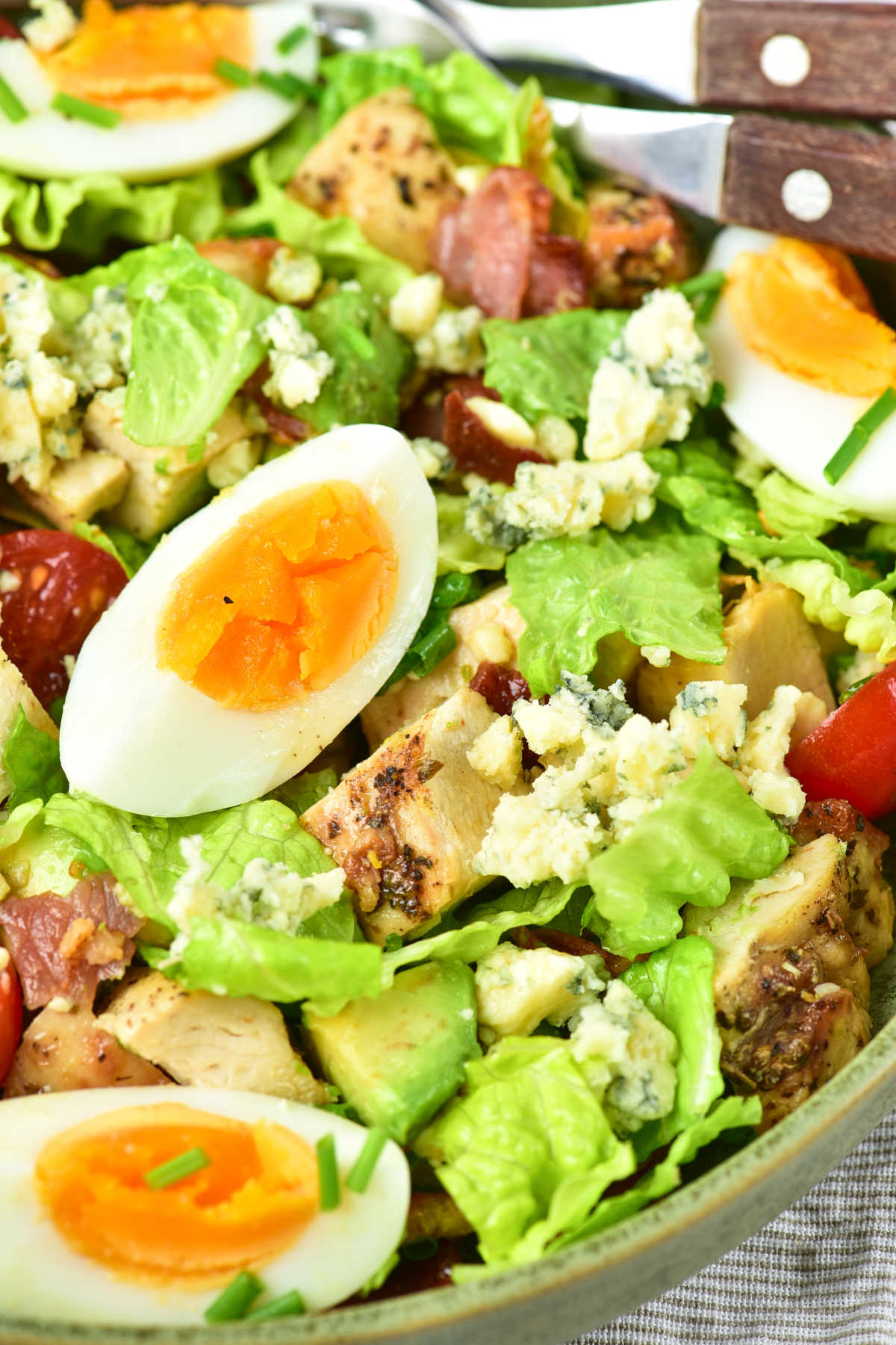 Close up of a tossed cobb salad showing the lettuce and toppings mixed together and ready to eat. 