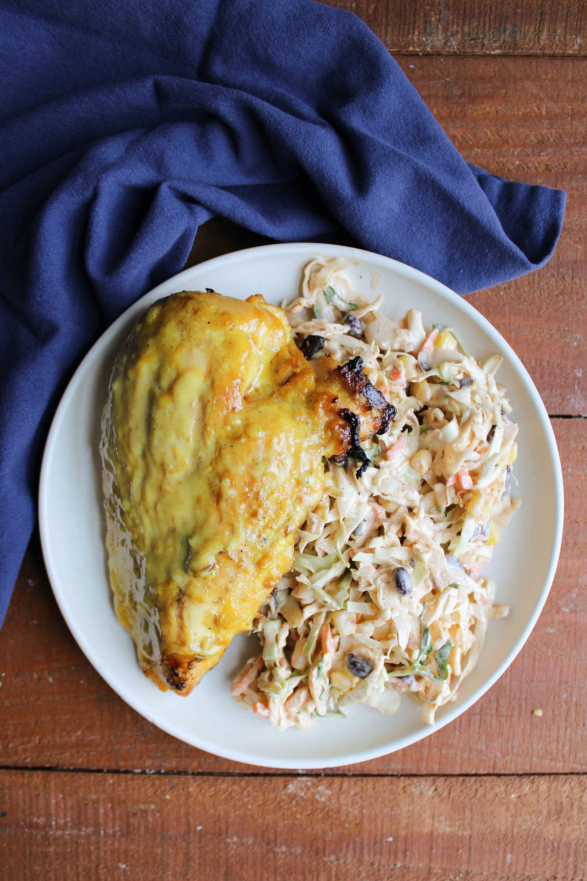 Dinner plate filled with large helping of southwestern slaw and a grilled yellow chicken breast. 