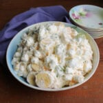 Serving bowl filled with grape supreme salad with bananas, oranges, grapes, pineapple, and mini marshmallows in a creamy dressing.