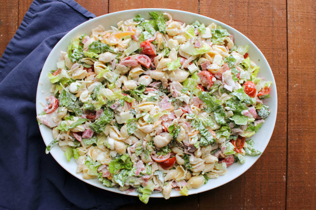 Grinder Pasta Salad 5 Large white serving bowl filled with grinder macaroni salad with meat, cheese, and veggies tossed with shell pasta and a light creamy dressing.