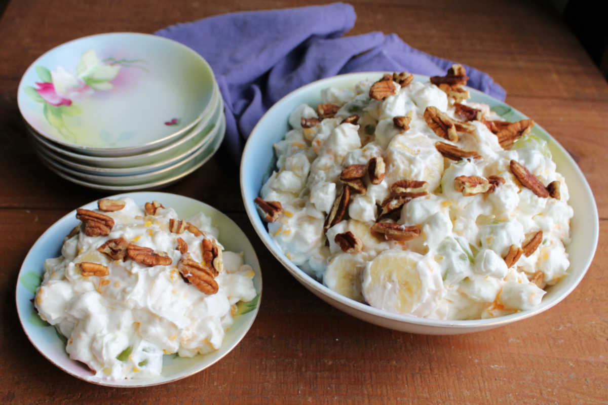 Old fashioned china bowls filled with grape supreme salad topped with pecan pieces. 