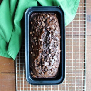 Loaf pan filled with baked chocolate zucchini bread fresh from the oven cooling on wire rack.