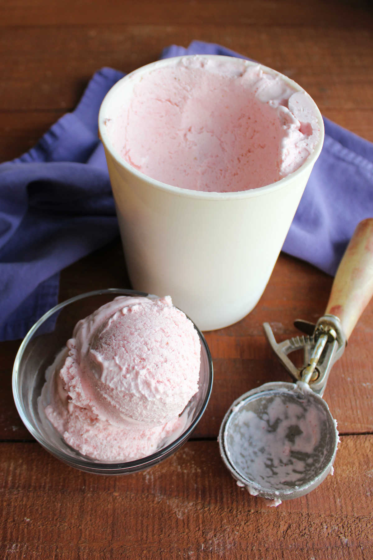 Homemade Strawberry Ice Cream Without Eggs 10 Serving of homemade strawberry ice cream next to a storage container and the antique ice cream scoop that served it.