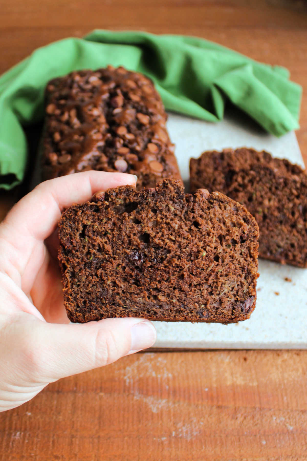 Hand holding a slice of moist double chocolate zucchini bread, ready to eat. 