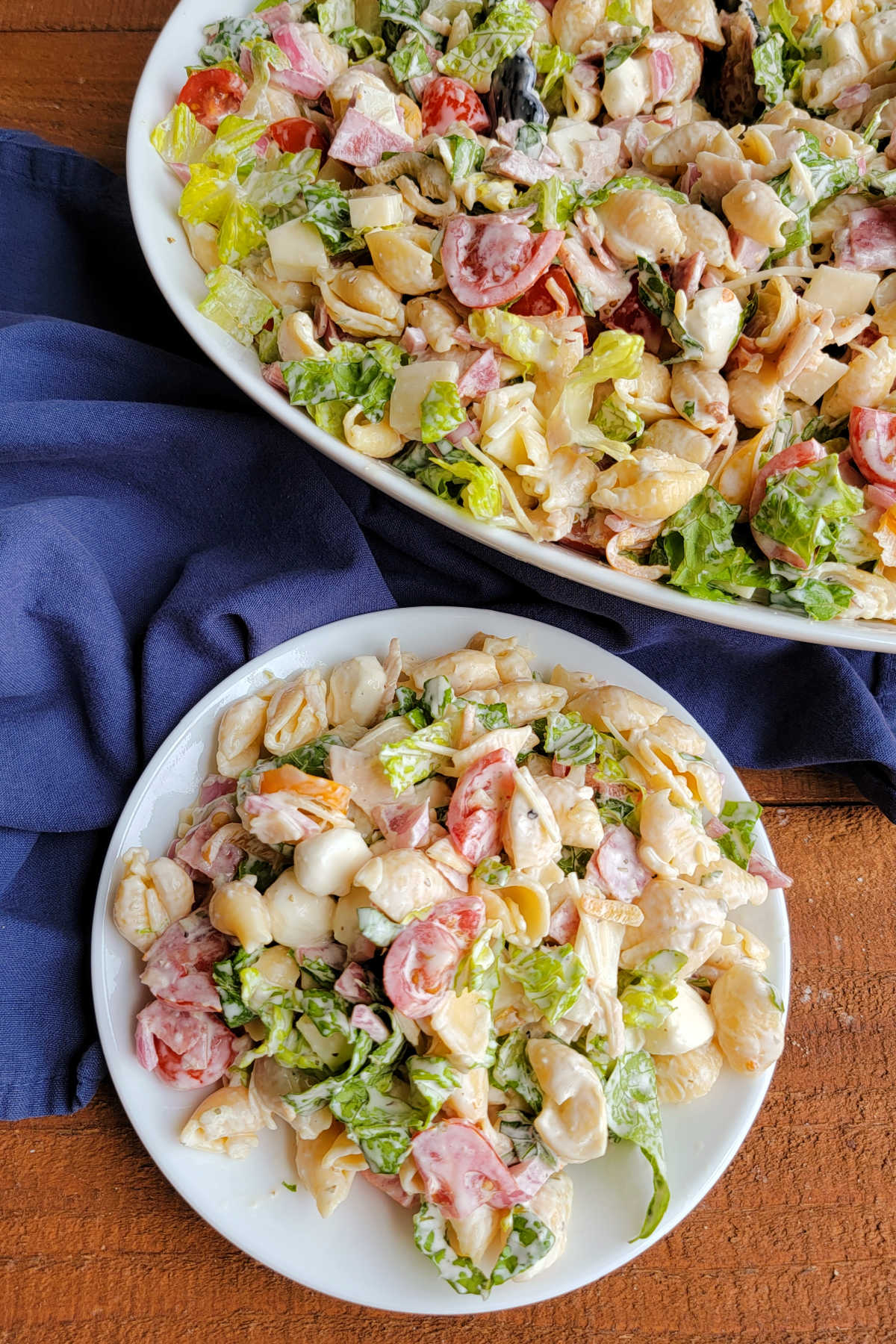 Grinder Pasta Salad 10 Serving of homemade grinder pasta salad on small plate next to a serving bowl with more pasta salad inside.