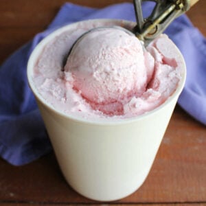 Homemade Strawberry Ice Cream Without Eggs 12 Ice cream scoop getting a ball of egg free strawberry ice cream out of a freezer container.