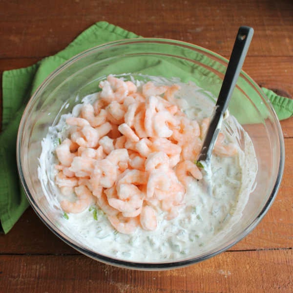 Shrimp Pasta Salad 8 Adding small frozen shrimp to bowl of creamy dill dressing with veggies inside.