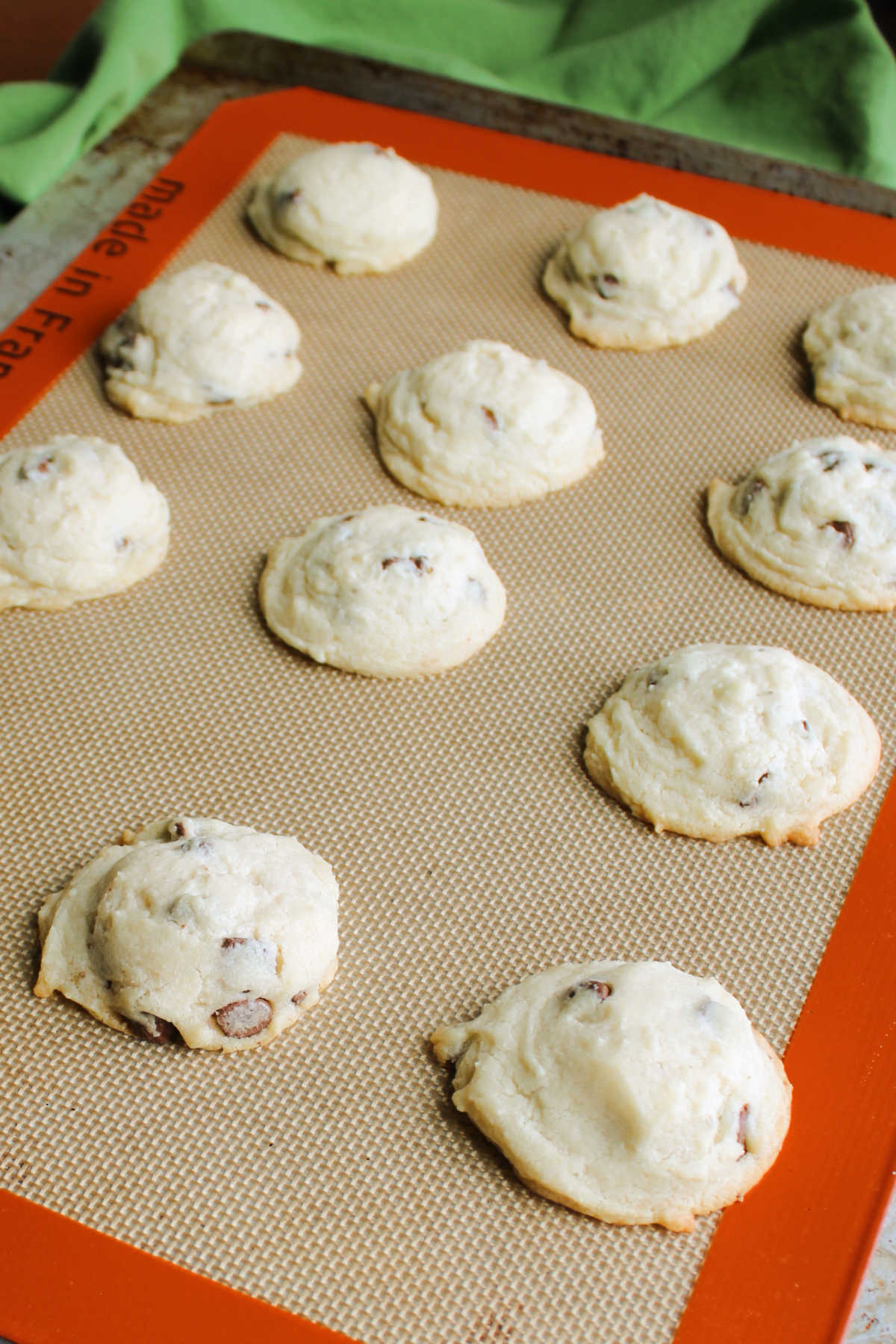 Freshly baked condensed milk cookies on cookie tray showing mounded shape, light color, and melty chocolate chips. 