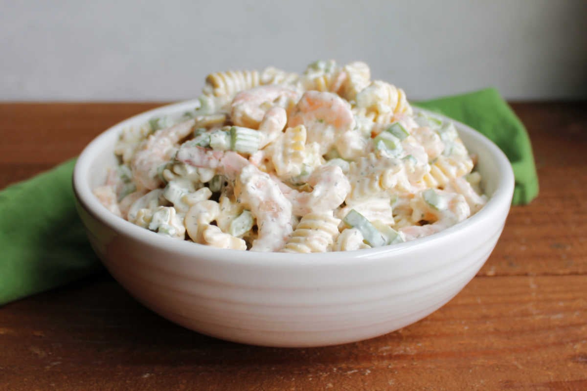 Shrimp Pasta Salad 5 White serving bowl piled with shrimp pasta salad with creamy dill dressing, small shrimp, noodles, and veggies, ready to be served.