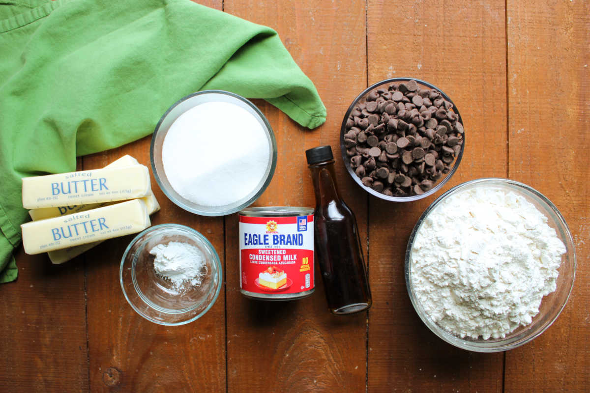 Ingredients including butter, sugar, flour, sweetened condensed milk, vanilla, baking powder, and chocolate chips ready to be made into condensed milk cookies with chocolate chips. 