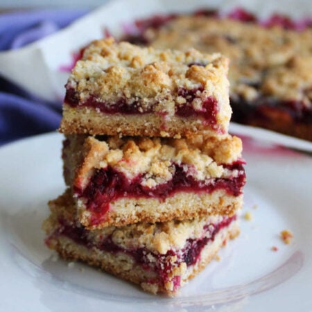 Blackberry Pie Bars 1 Three blackberry pie bars stacked on top of each other showing the crust layer, thick fruity filling and butter crumb topping.