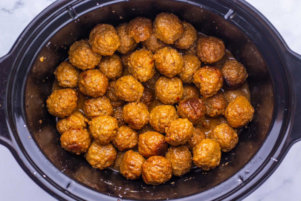 Crockpot filled with meatballs cooked in a thick sweet and savory Asian inspired sauce, ready to be served. 