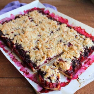 Blackberry Pie Bars 18 Blackberry pie bars cut into squares on cutting board.