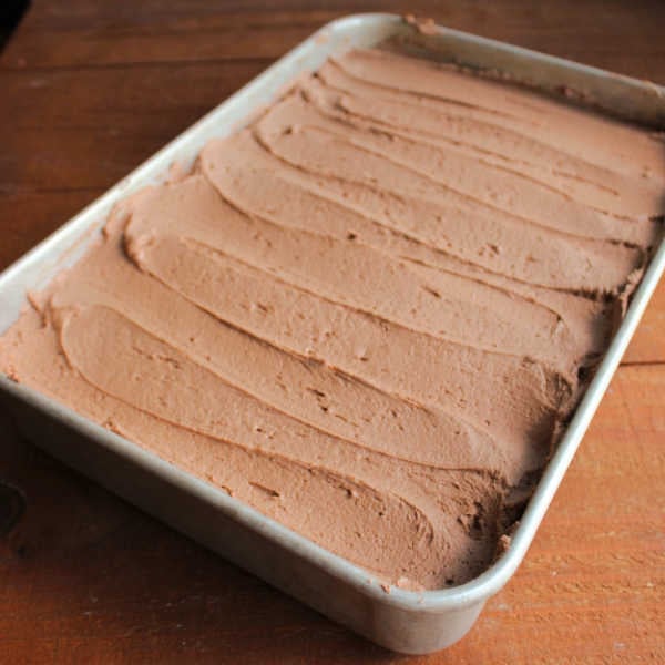 Light chocolate buttercream spread over cake in 9x13-inch pan. 