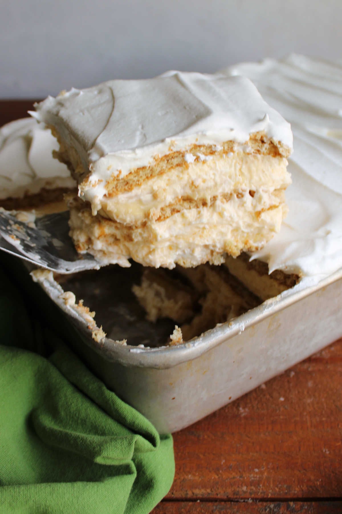 Banana Pudding Icebox Cake 6 Spatula lifting a square of banana pudding icebox cake out of a vintage cake pan, showing the layers of pudding, banana slices, and graham crackers.