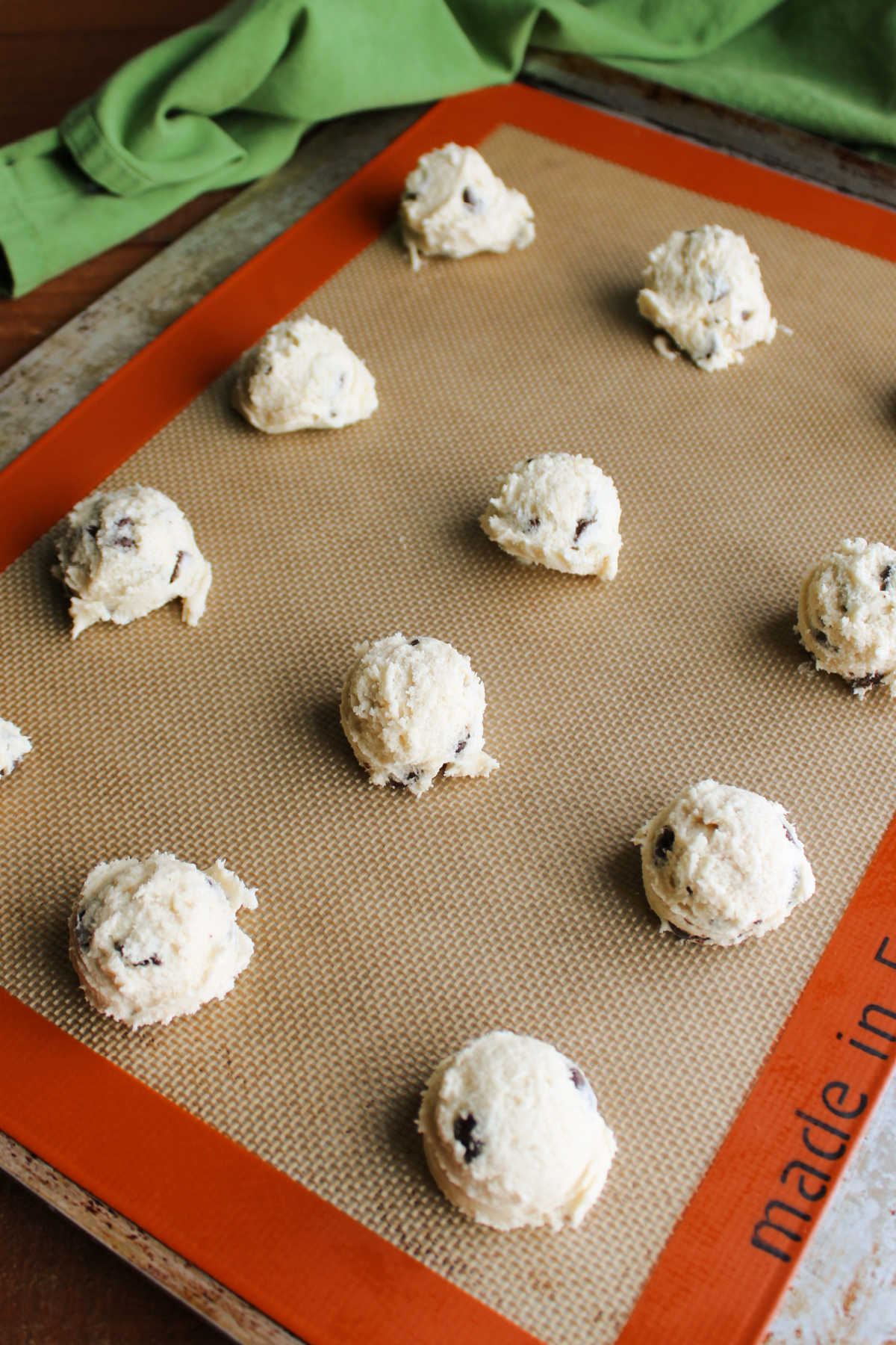 Scoops of condensed milk cookie dough on silpat lined cookie tray. 
