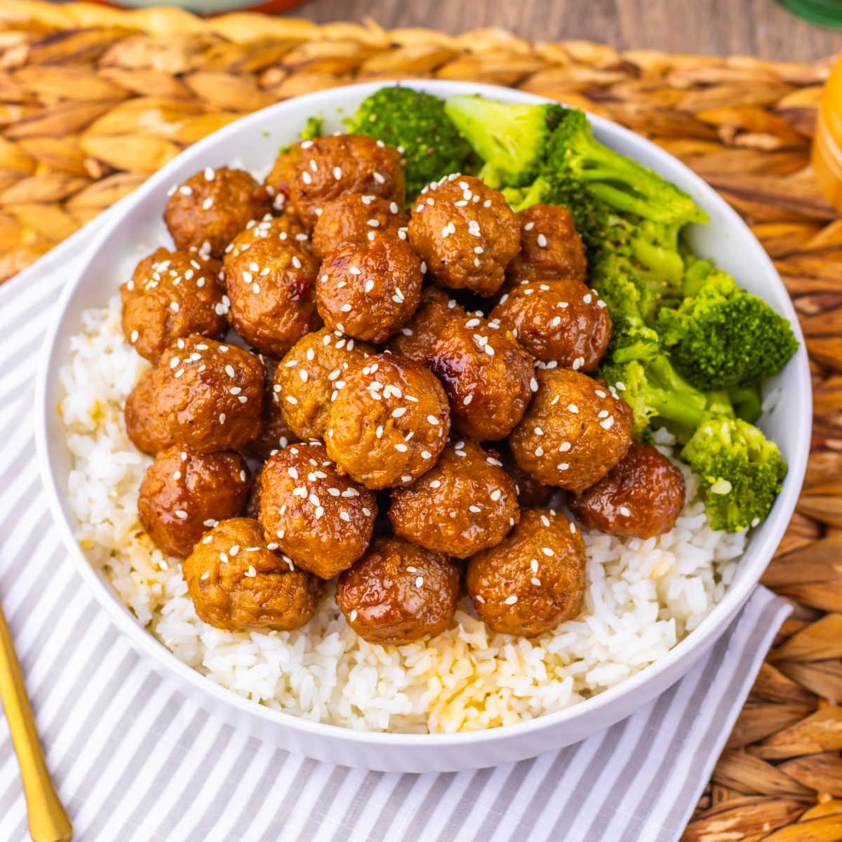 Crockpot Mongolian Meatballs 5 Plate filled with white rice topped with mongolian meatballs with sticky sauce and some sesame seeds served with a side of broccoli, ready to eat.