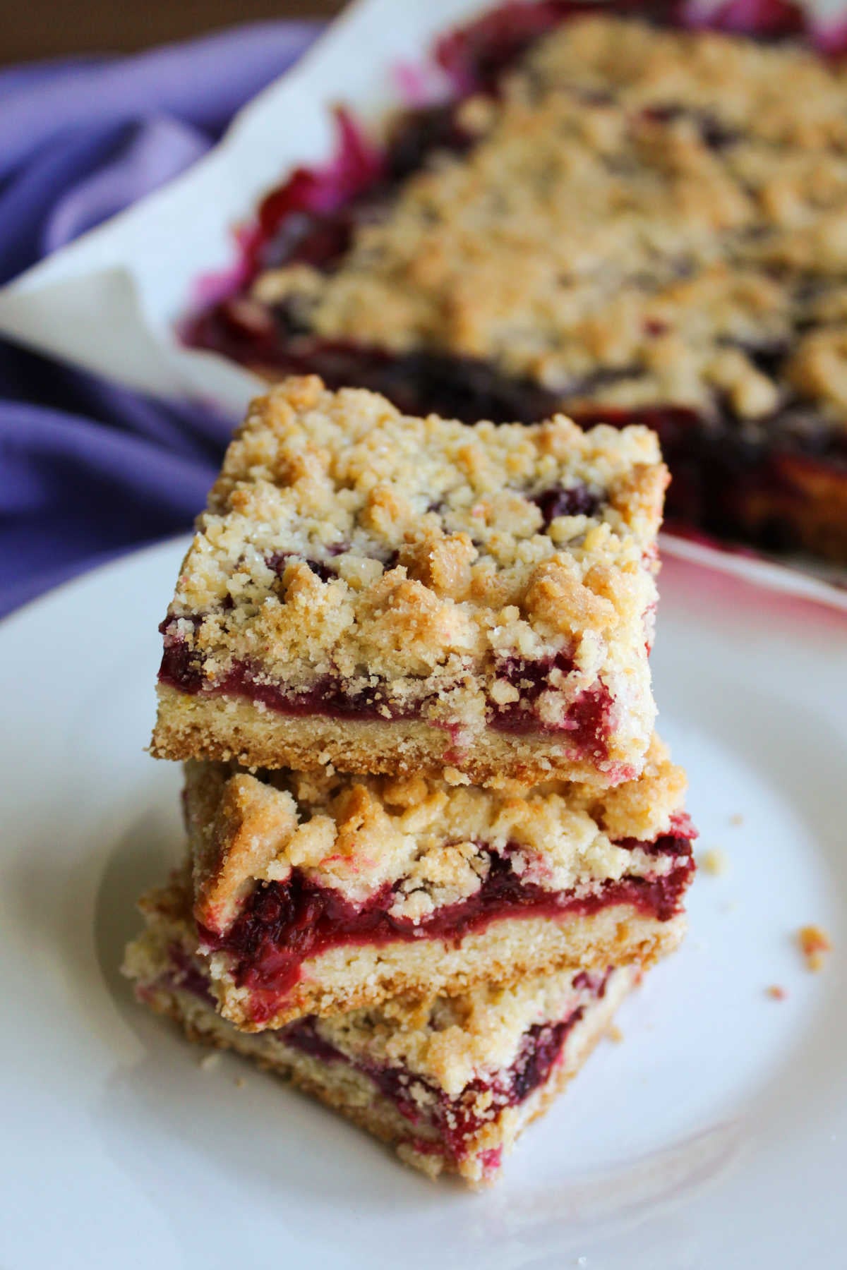 Blackberry Pie Bars 7 Stack of blackberry pie bars with cookie style crust, blackberry filling, and golden brown crumb topping.