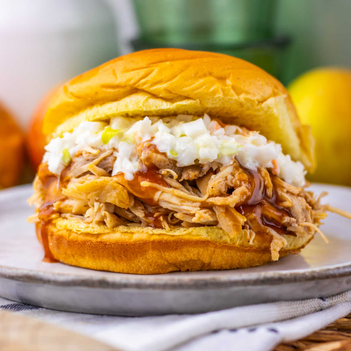 Brioche bun filled with pulled chicken with apple cider bbq sauce and a creamy coleslaw, ready to eat.