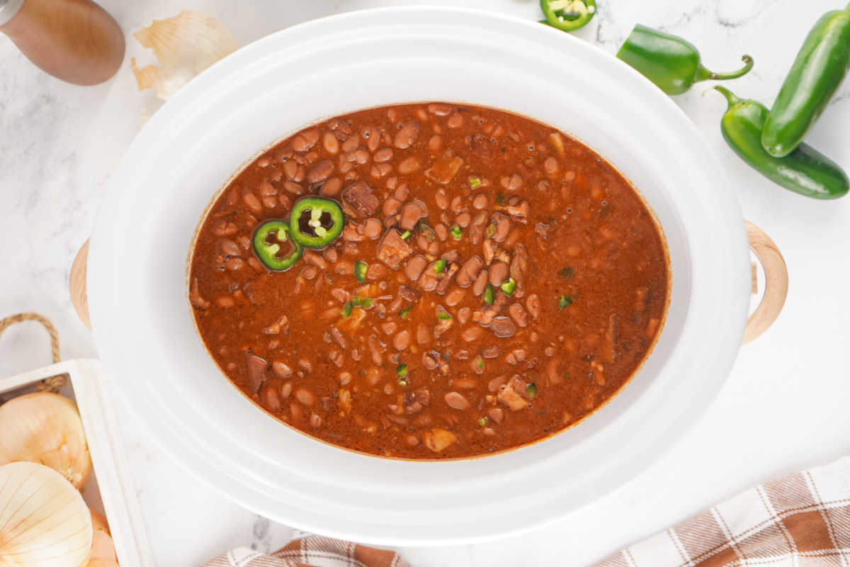 Crockpot Baked Beans With Dried Beans 7 Crockpot filled with finished baked beans in thick read sauce topped with a couple of slices of fresh jalapeno pepper.