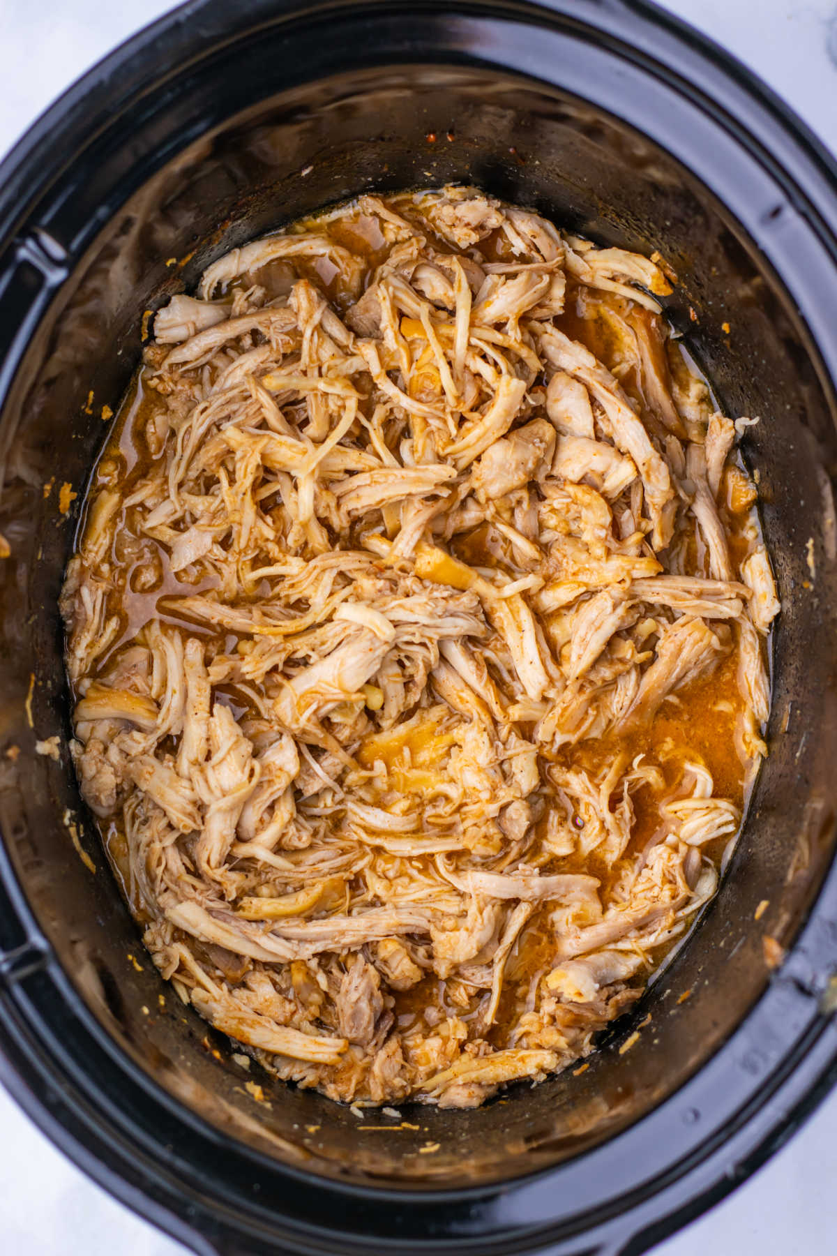 Crockpot with pulled chicken in apple cider bbq sauce mixture, ready to be served. 