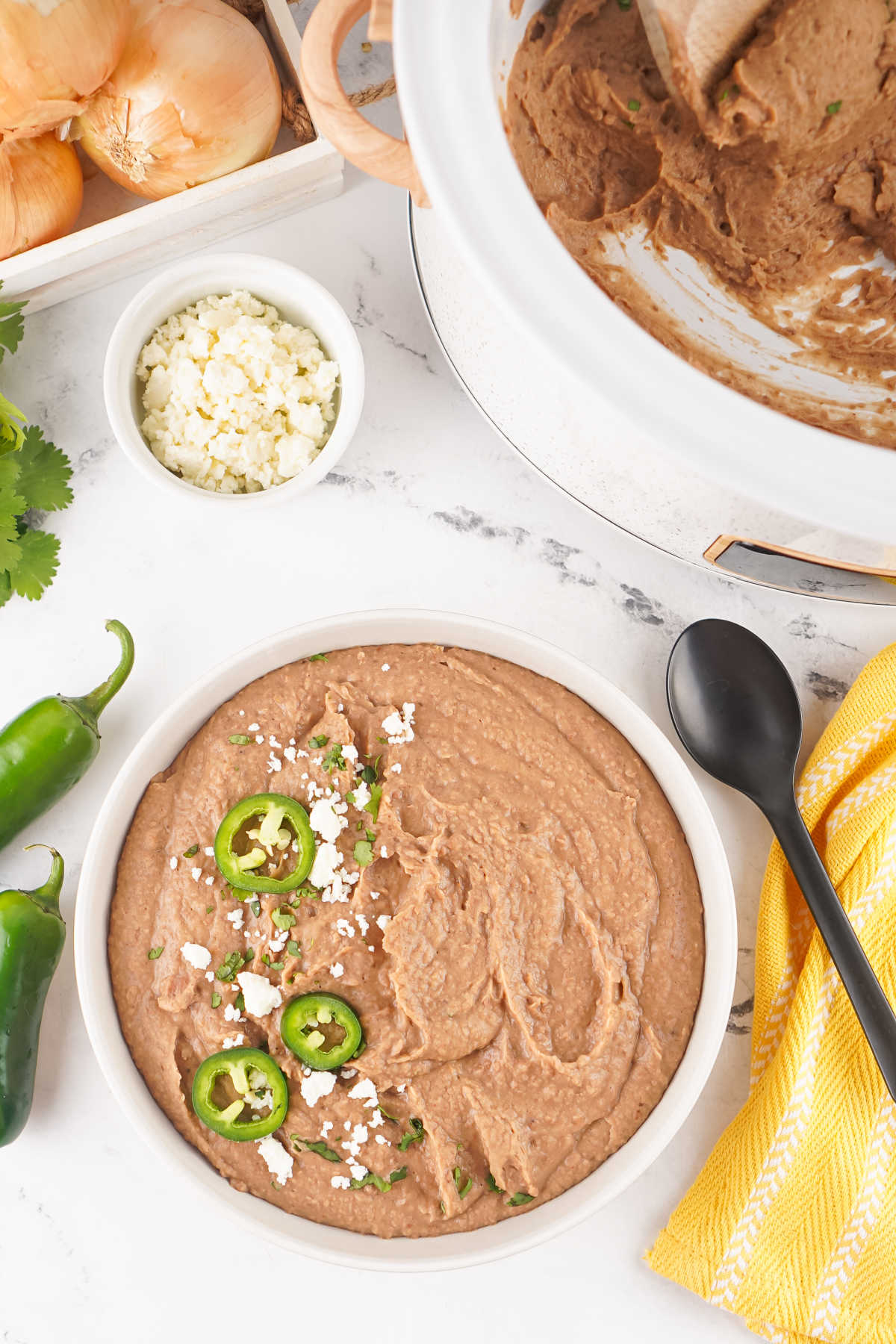Bowl of refried beans next to the crockpot they were cooked in, ready to be served. 