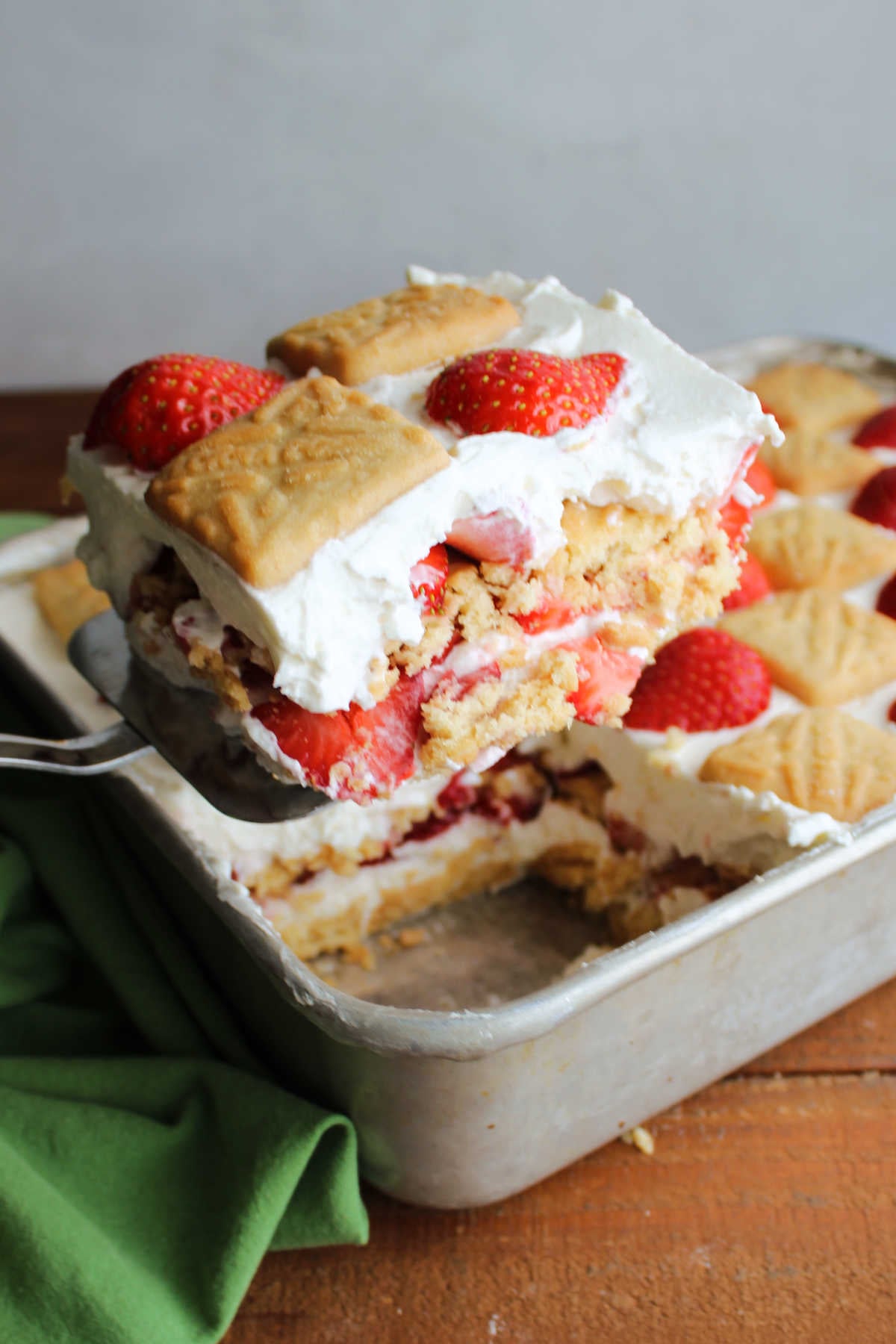 Spatula lifting square of strawberry shortcake icebox cake out of pan. 