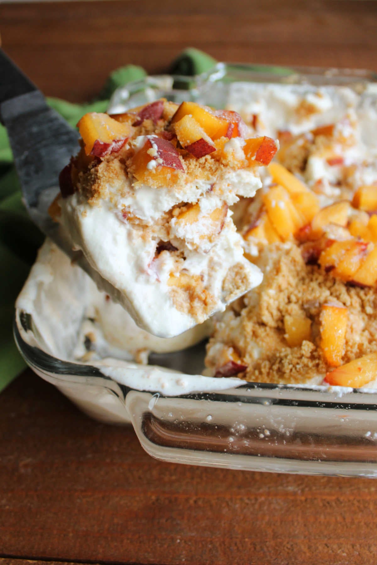 Peaches and Cream Icebox Cake 10 Spatula lifting creamy peach icebox cake out of the square pan it was made in.