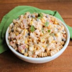 Serving bowl filled with pasta salad with creamy taco dressing, chunks of chicken, corn, black beans, tomatoes, onion, jalapeno and cilantro.