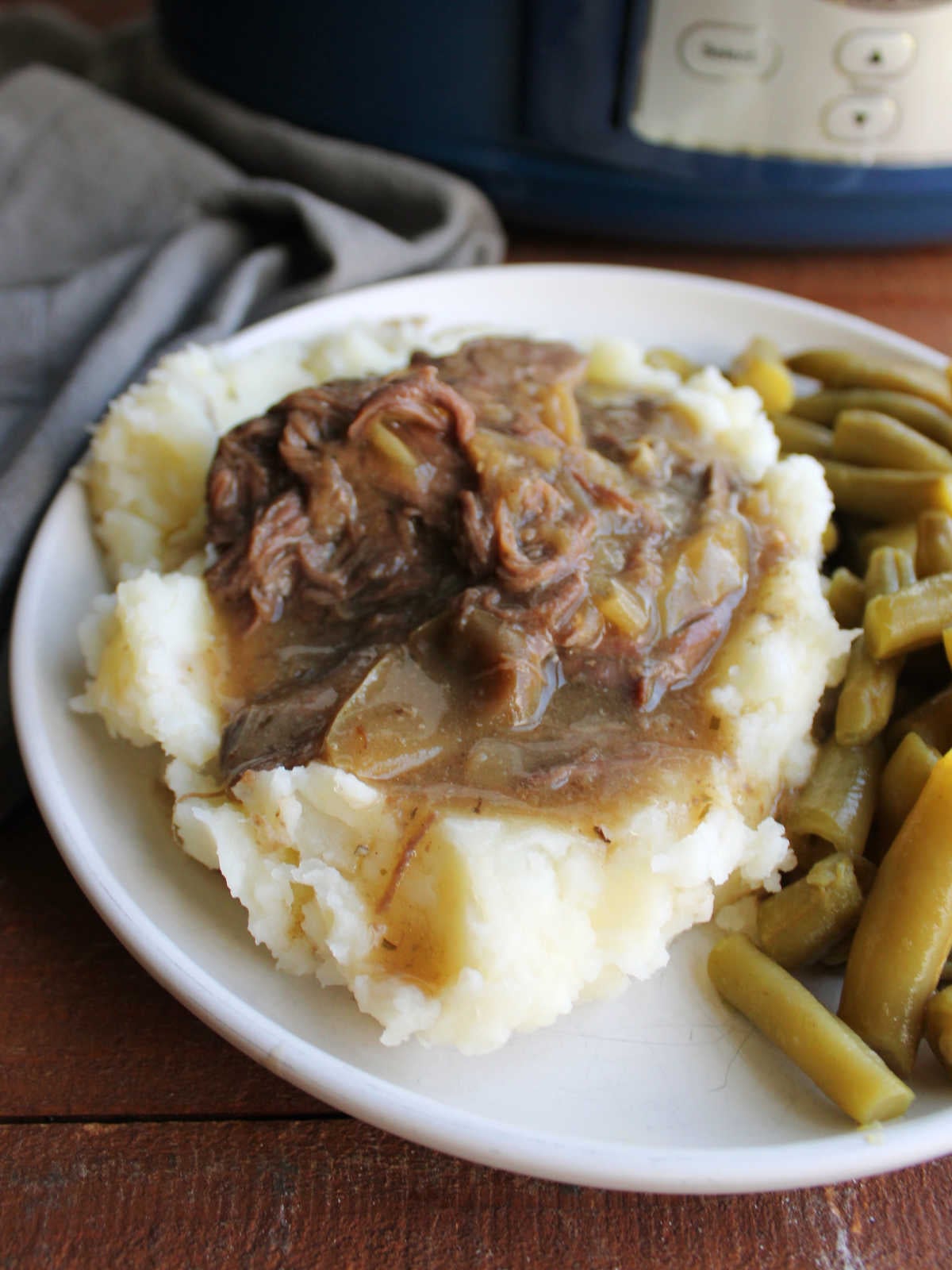 Close up of a heap of shredded venison in gravy served over smashed potatoes. 