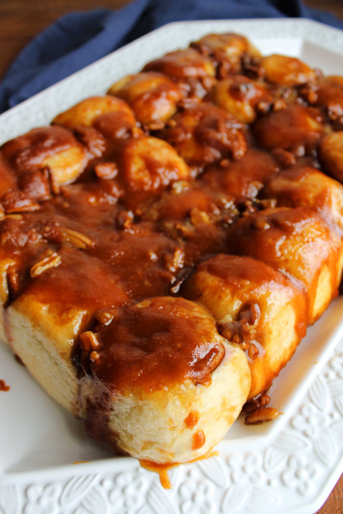 Freshly baked caramel pecan rolls dumped onto a platter with butterscotch and pecan topping all gooey on top of the rolls. 